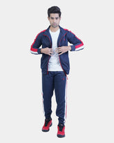 Man wearing a navy tracksuit with red accents on a light gray background