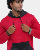 Man wearing a red and black hoodie with a logo on a light gray background