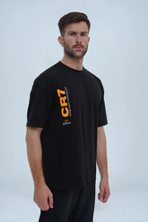 A black oversized drop-shoulder CR7 edition t-shirt by XEA Clothing, featuring a bold vertical CR7 logo on the front and a dynamic graphic of Cristiano Ronaldo’s iconic celebration on the back. Designed for a relaxed, streetwear-inspired fit with a trendy drop-shoulder silhouette. -  CR7 Ronaldo Oversized T-Shirt - Xea Clothing