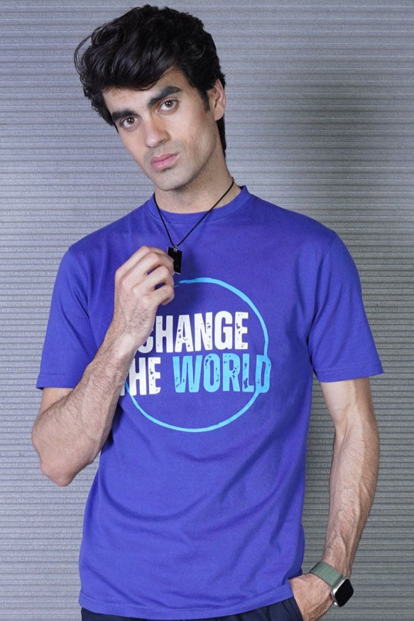 A person standing in front of a door wearing a blue crew neck t-shirt with the message 'CHANGE THE WORLD' printed on the front.