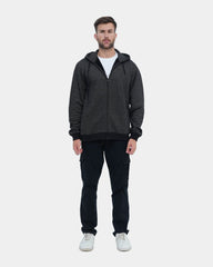 Man wearing a dark gray hoodie and black pants on a light blue background