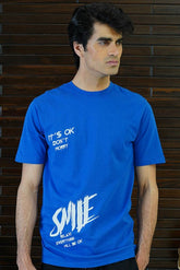 Man wearing a blue t-shirt with text against a wooden background