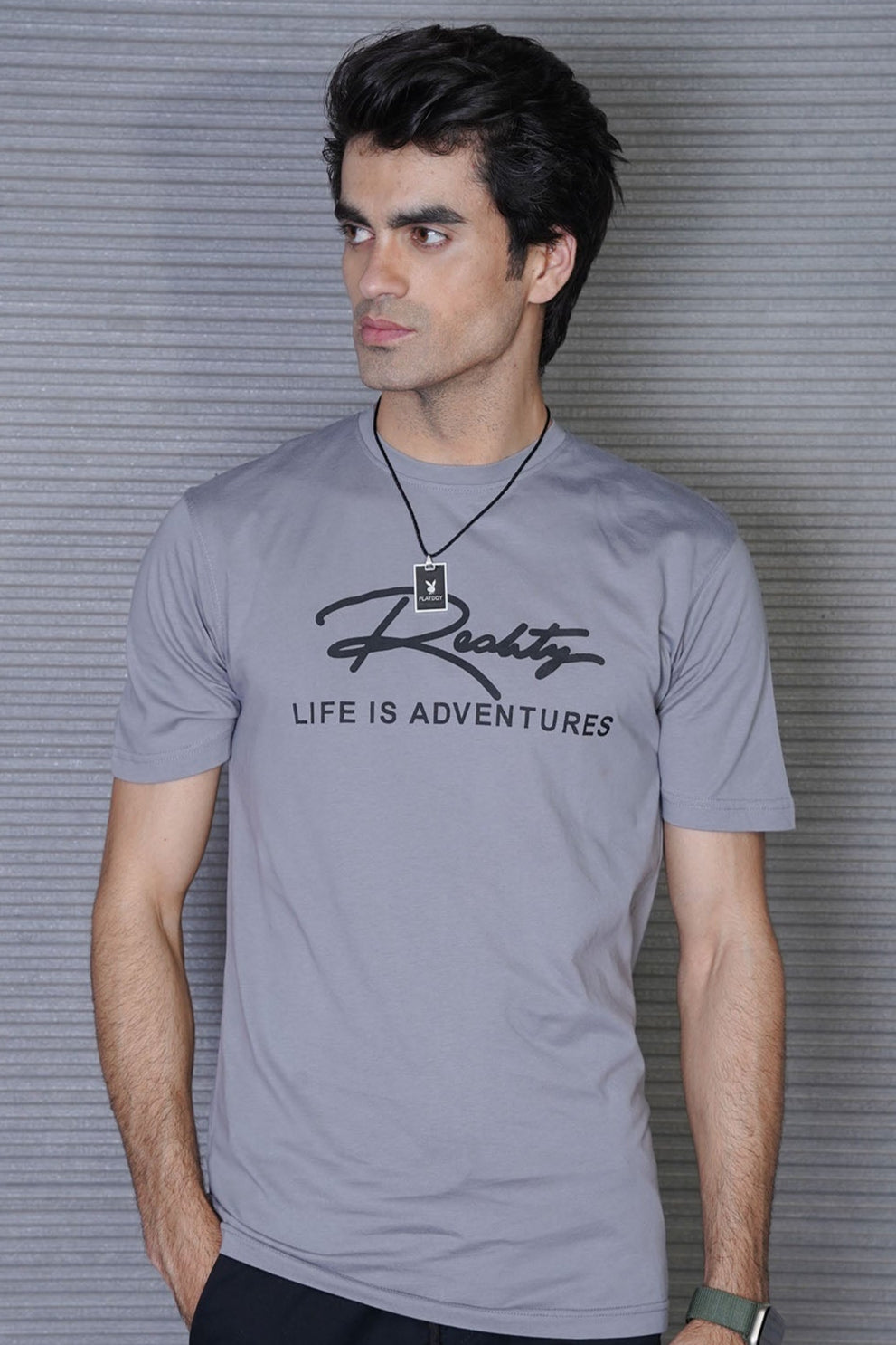 Man wearing a gray t-shirt with 'Rocky' branding and text against a striped background