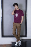 A person wearing a maroon graphic t-shirt with a horse design, paired with brown trousers and white sneakers.
