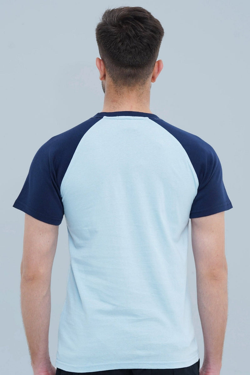 Person wearing a light blue and navy baseball shirt on a gray background