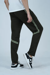 A male model wearing olive green jogger pants with a contrasting half stripe, paired with a white t-shirt and white sneakers.