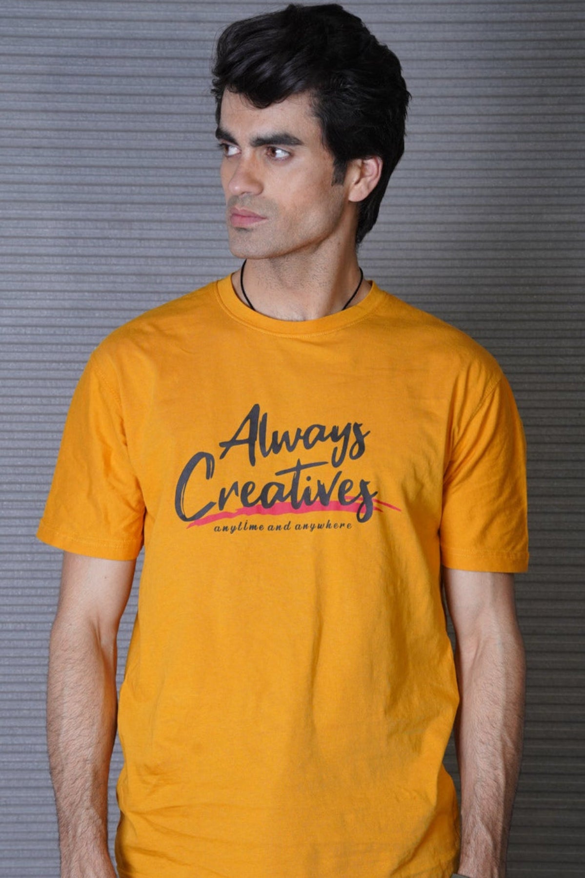 Man wearing a mustard yellow t-shirt with 'Always Creatives' text