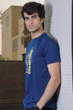 Man wearing a blue t-shirt with 'Champions' text leaning against a wall.