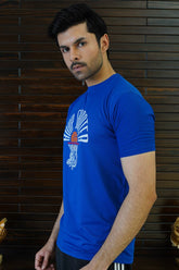 Man wearing a blue t-shirt with a logo against a wooden panel background