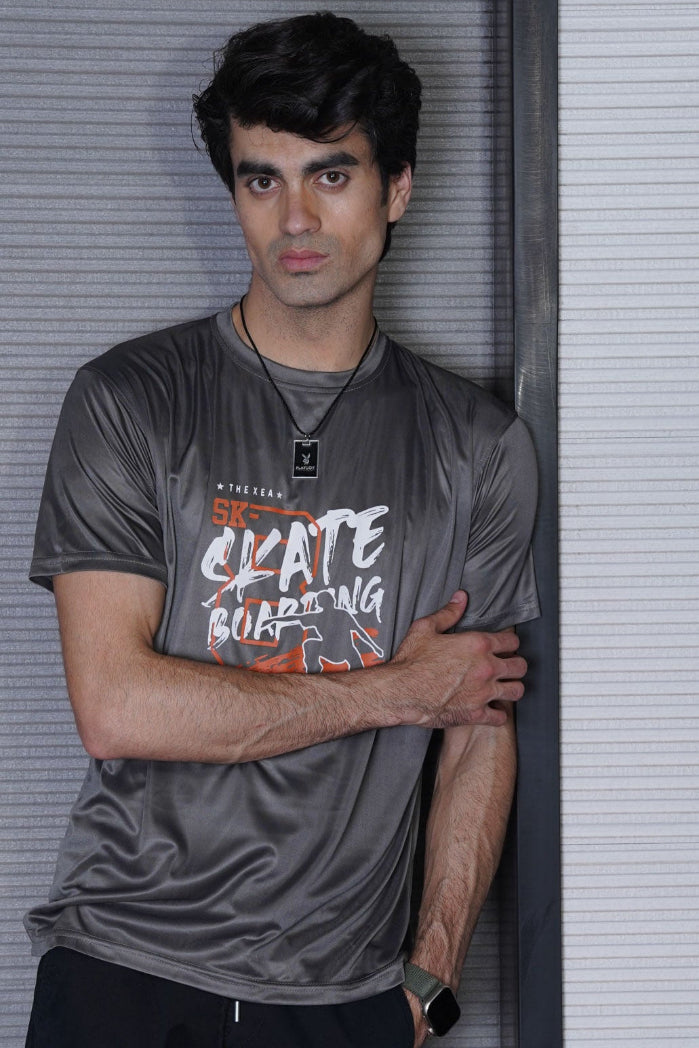 Person wearing a gray t-shirt with 'Skate Boarding' text against a light-colored wall.