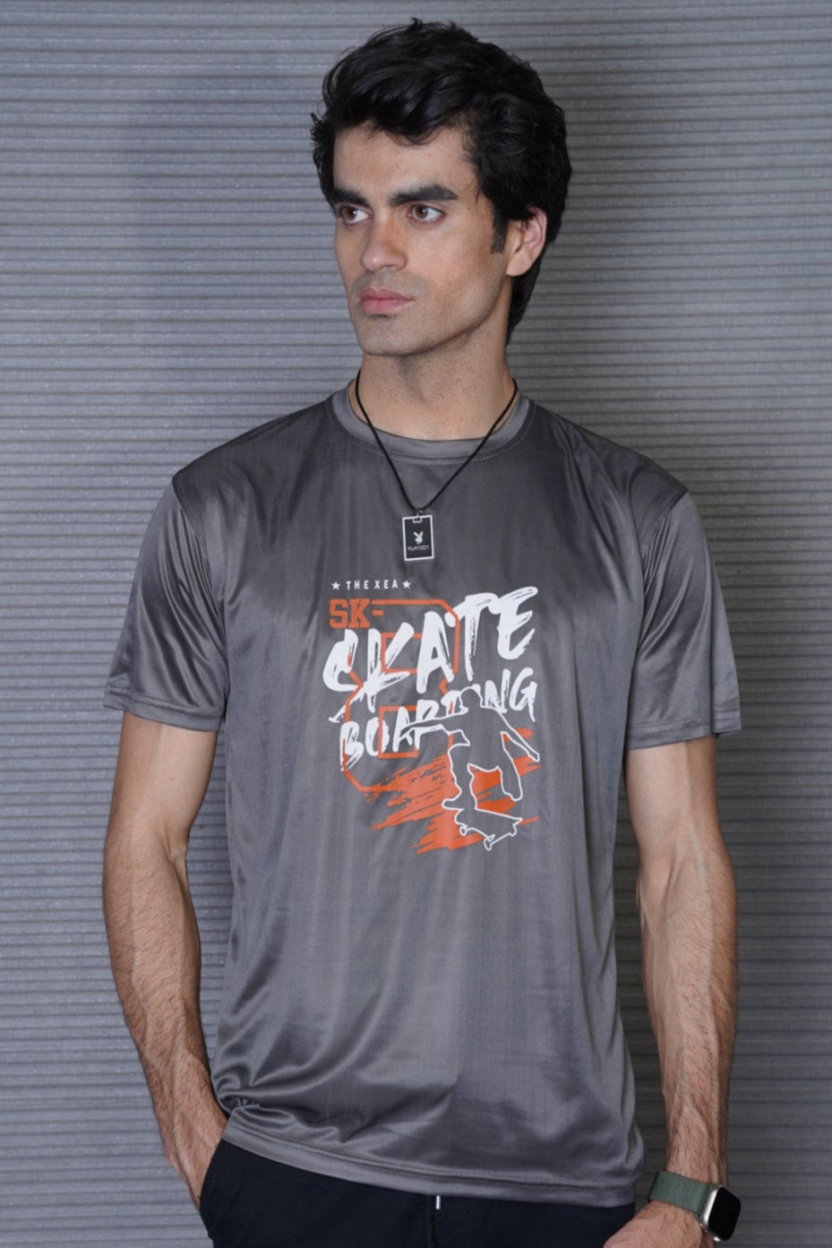 A person wearing a gray t-shirt with the text 'SKATE BOARDING' and a graphic design related to skateboarding.