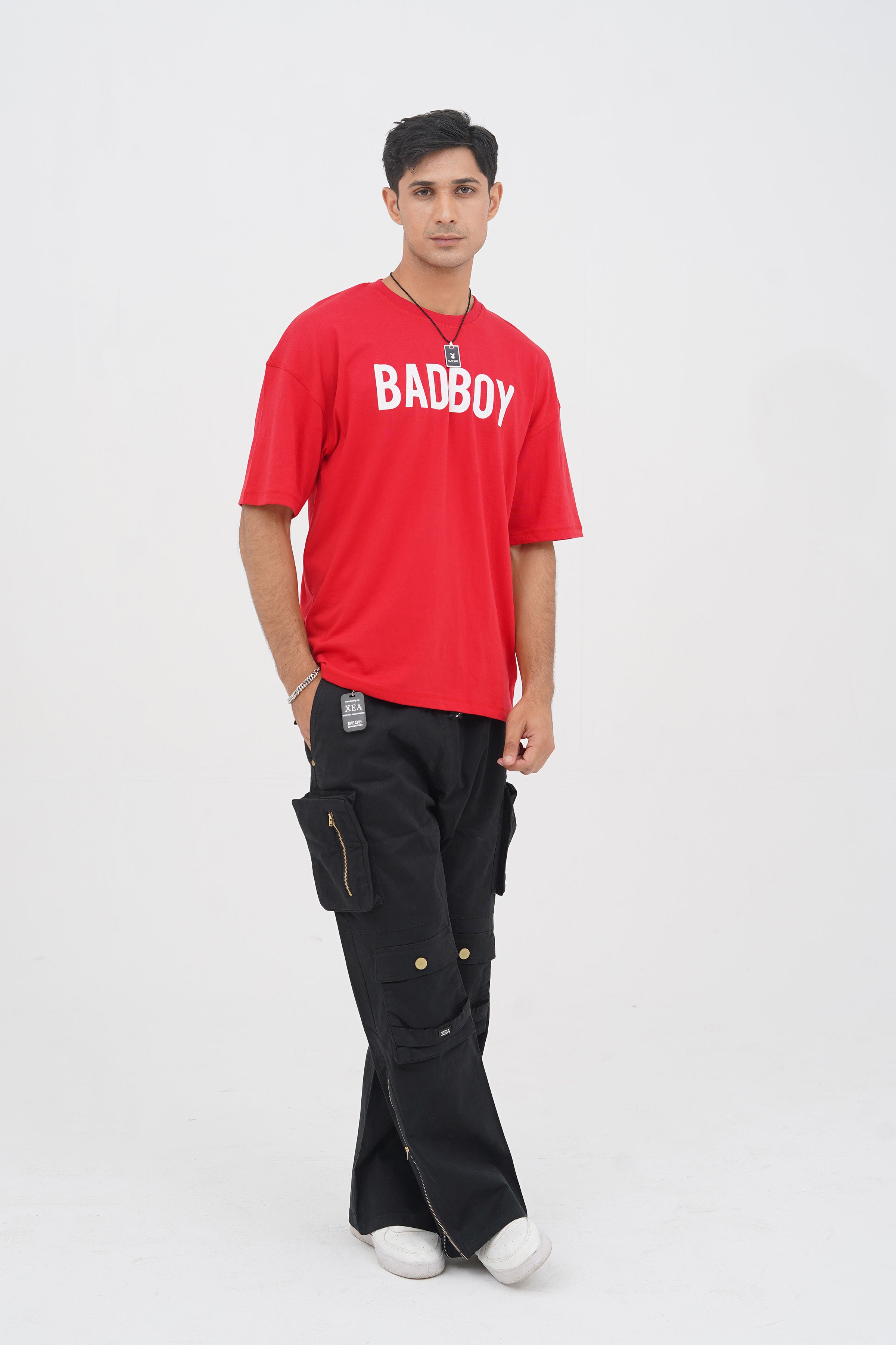 A male model wearing black cargo pants and a red t-shirt with the text 'BADBOY' on it.