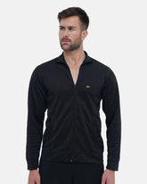 Man wearing a black zip-up sweatshirt with a visible brand logo on a light gray background