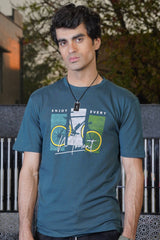 Man wearing a teal t-shirt with a graphic design outdoors