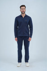 Man wearing a navy tracksuit on a light gray background