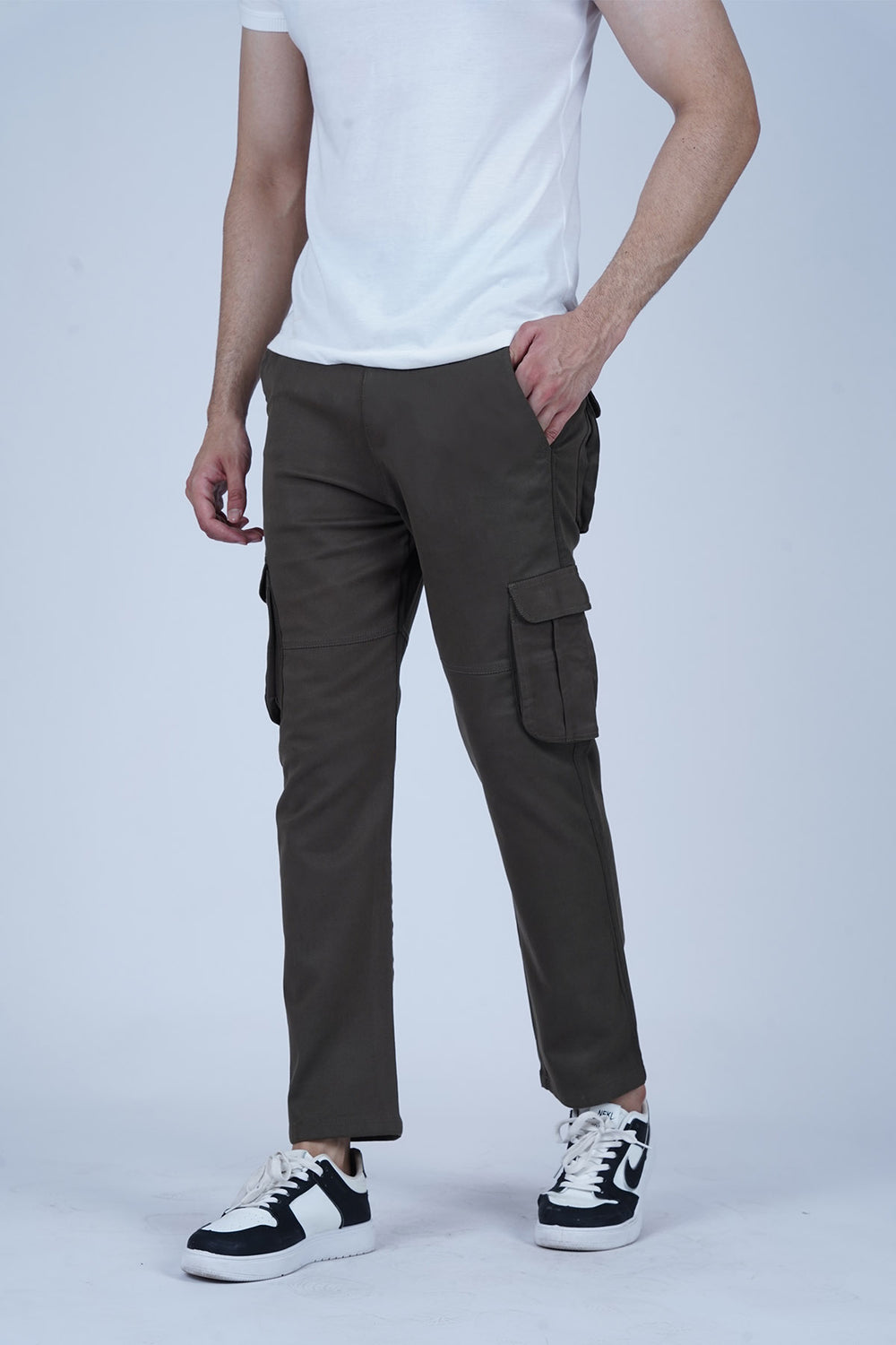A male model wearing green cargo pants with a white t-shirt, standing against a plain background.