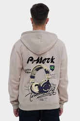 Person wearing a beige hoodie with a graphic design on the back, standing against a white background