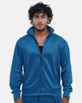 Man wearing a blue tracksuit against a light gray background