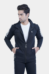 Man wearing a black tracksuit with white stripes on a light gray background