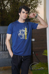 Man wearing a blue t-shirt with text and graphics, standing outdoors.