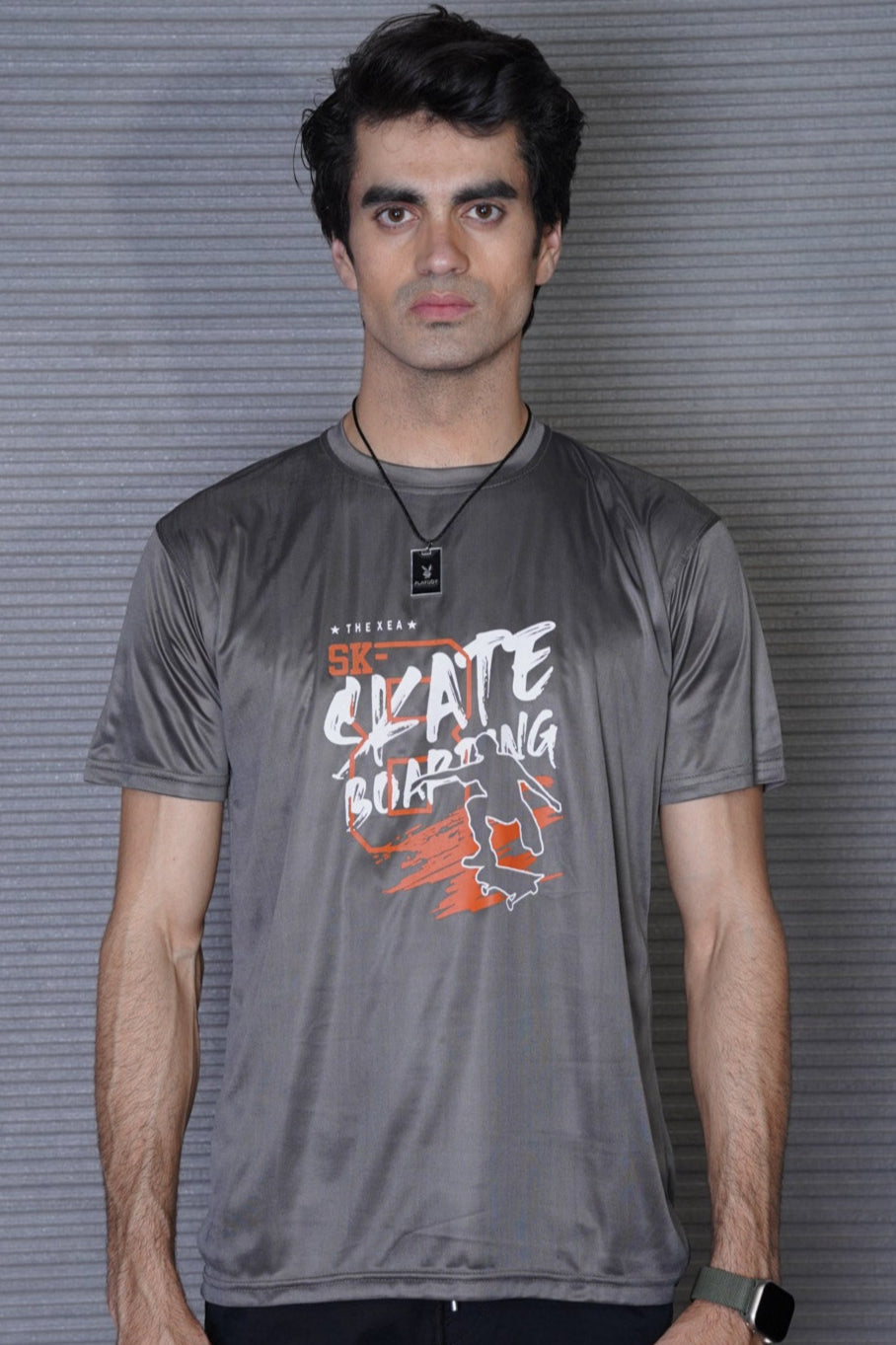 Man wearing a gray t-shirt with graphic design against a textured wall