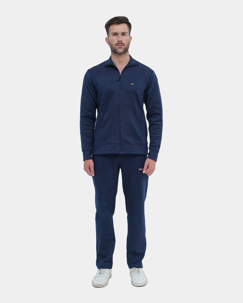 Man wearing a navy tracksuit with a logo on a light gray background