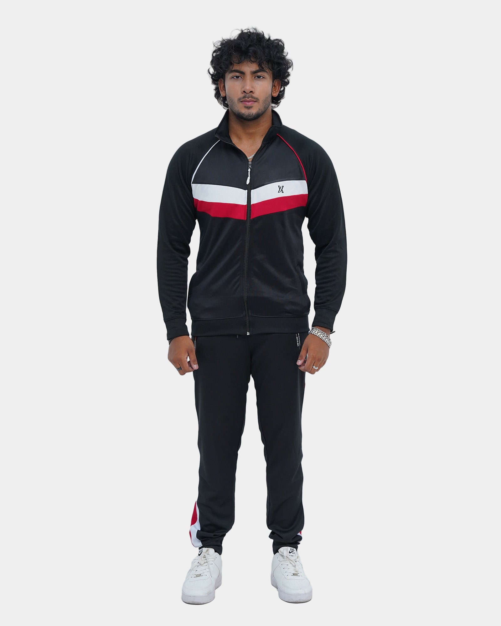 Man wearing a black tracksuit with red and white accents on a light gray background