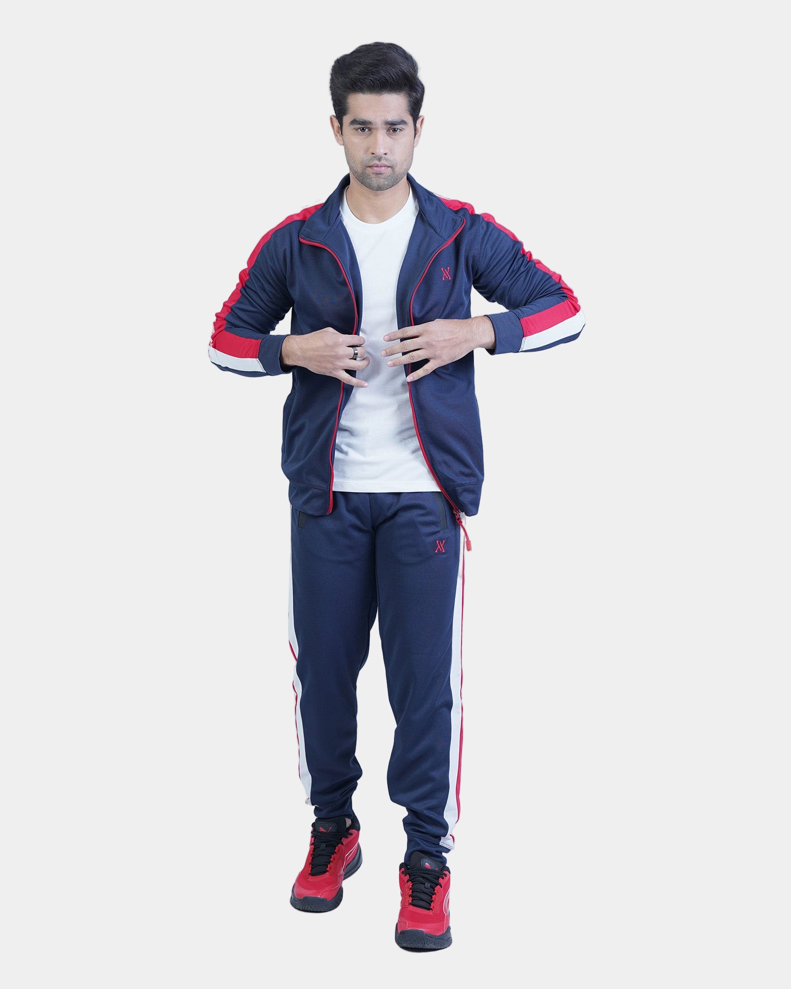 Man wearing a navy tracksuit with red accents on a light gray background