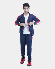 Man wearing a navy tracksuit with red accents on a light gray background