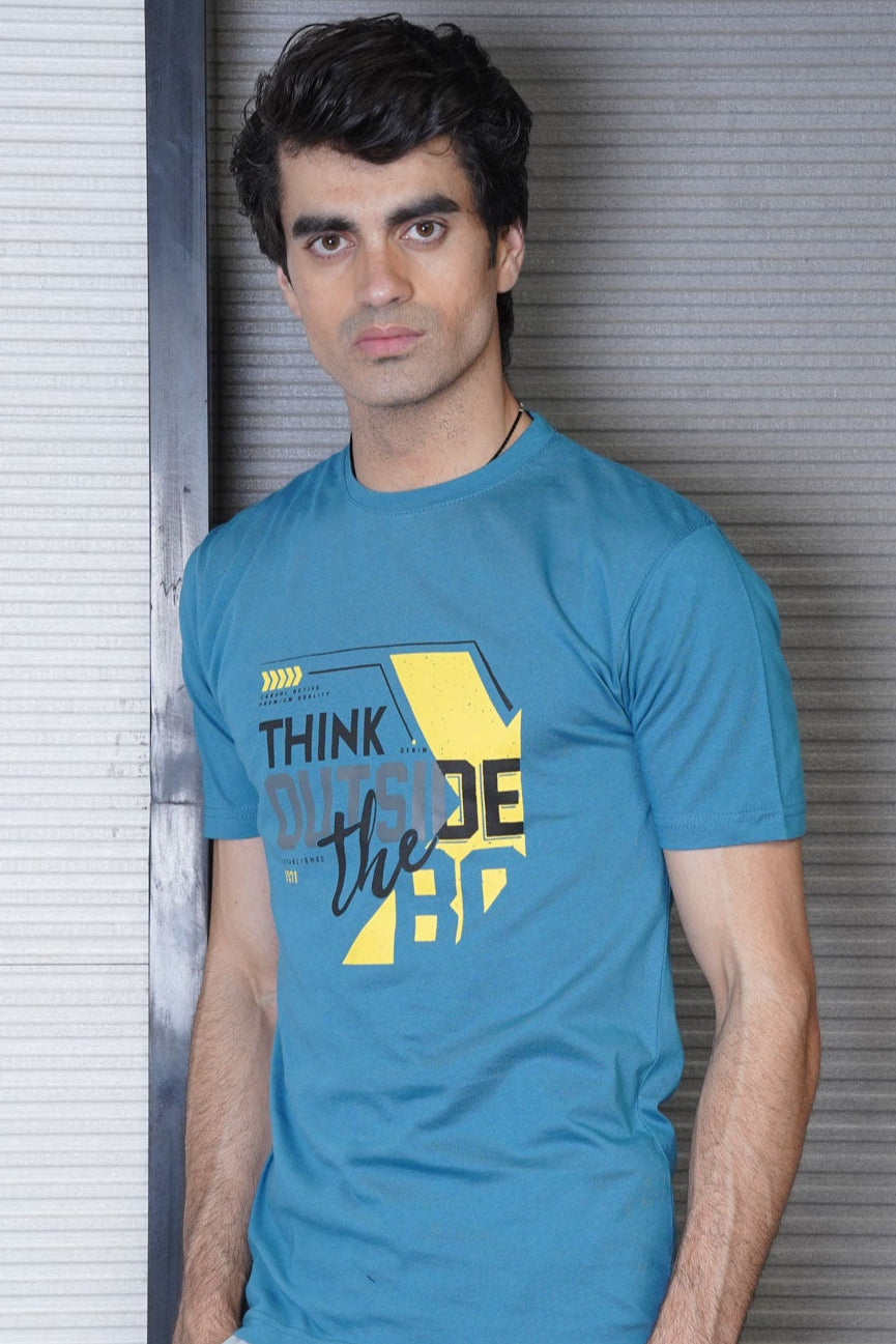 Man wearing a blue t-shirt with 'Think Outside the Box' text against a metallic background