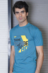 Man wearing a blue t-shirt with 'Think Outside the Box' text against a metallic background