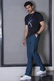 Man wearing a black t-shirt with a graphic design and blue pants against a gray wall.