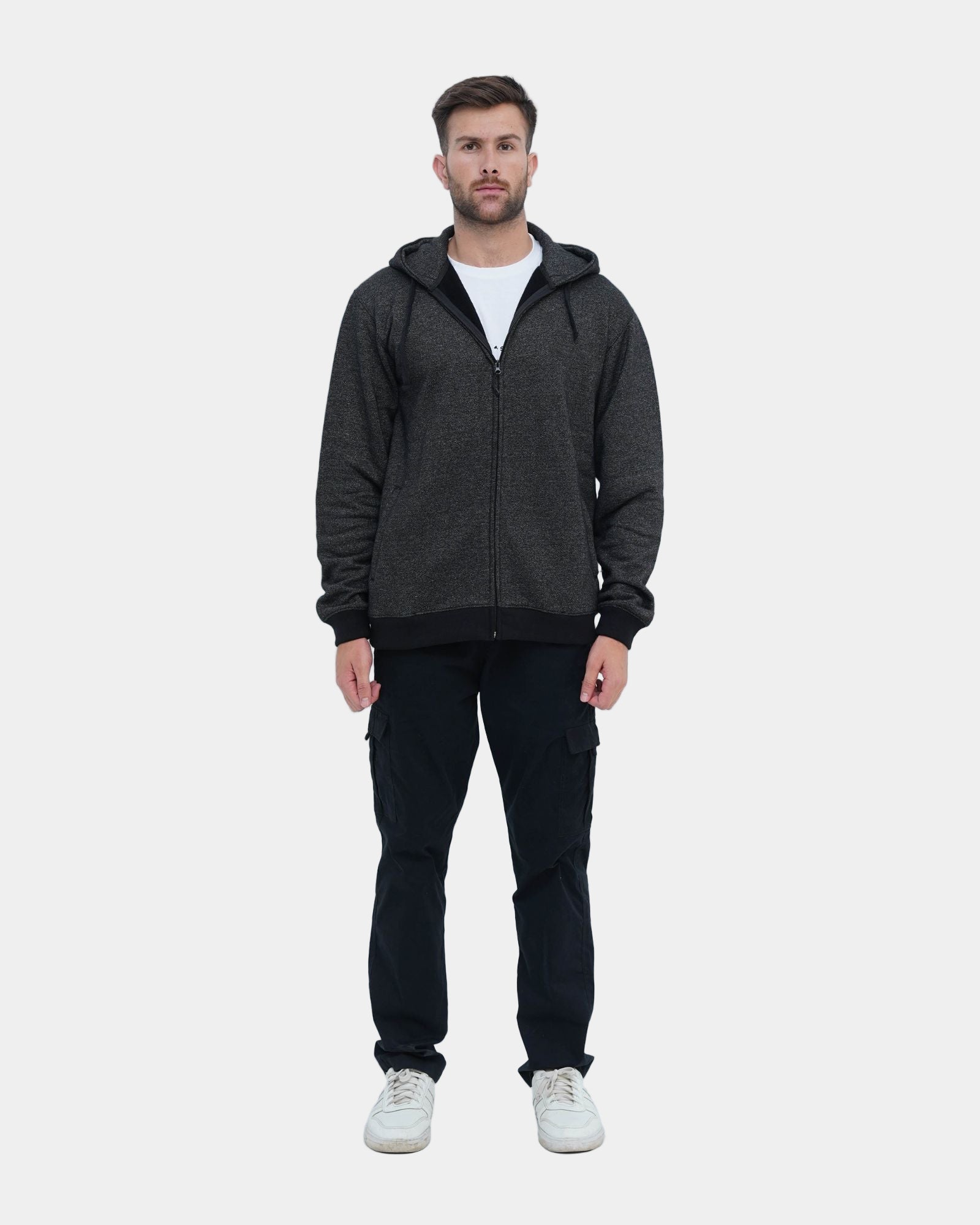 Man wearing a dark gray hoodie and black pants on a light blue background