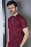 Man wearing a maroon t-shirt with a logo against a metallic background