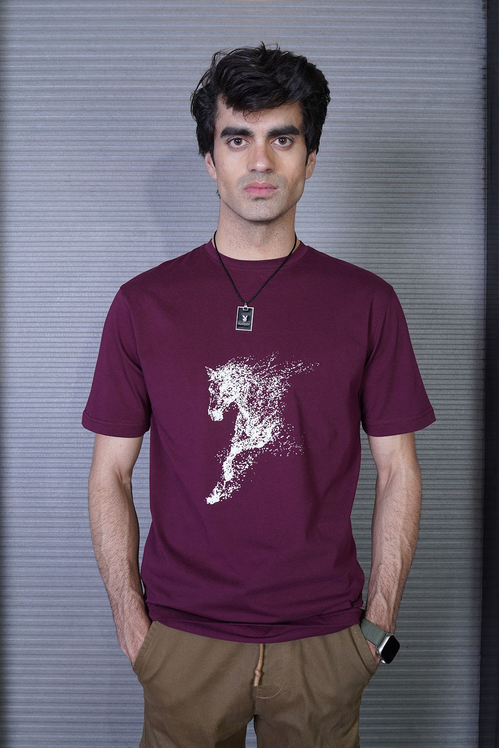 Man wearing a maroon t-shirt with a white graphic design on a striped background