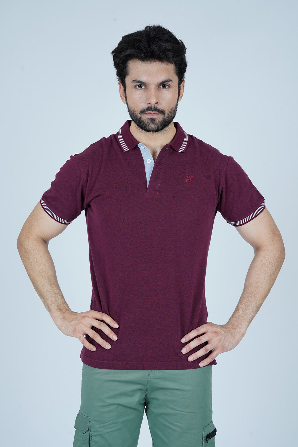 Man wearing a maroon polo shirt with a brand logo on a light gray background