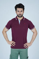 Man wearing a maroon polo shirt with a brand logo on a light gray background