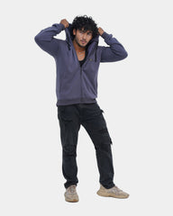 Man wearing a purple hoodie and black cargo pants on a light gray background
