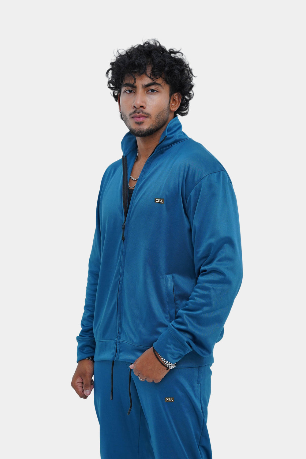 Man wearing a blue tracksuit against a light gray background