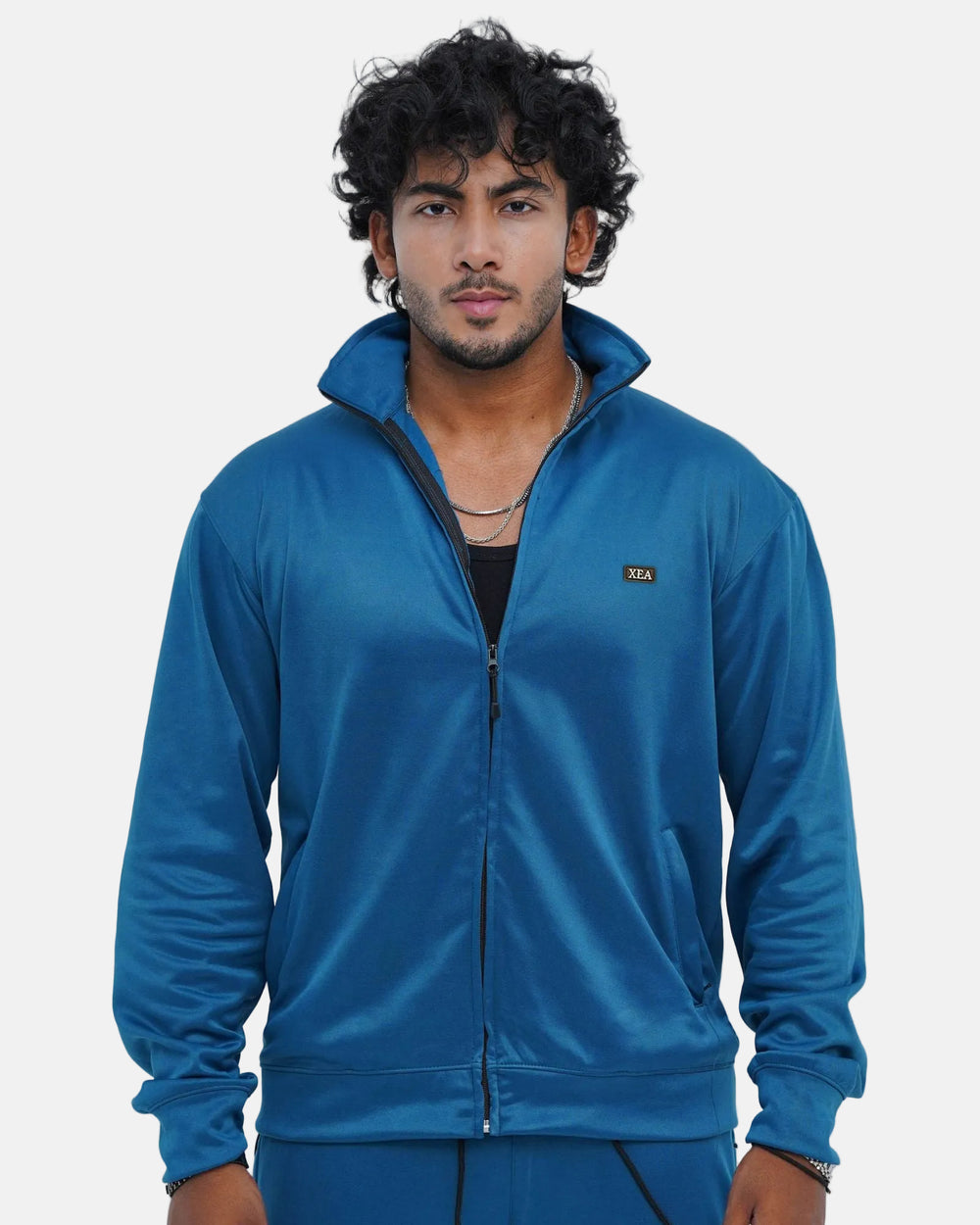 Man wearing a blue tracksuit against a light gray background