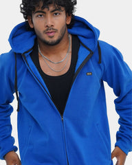 Man wearing a blue hoodie with a brand logo on a light gray background